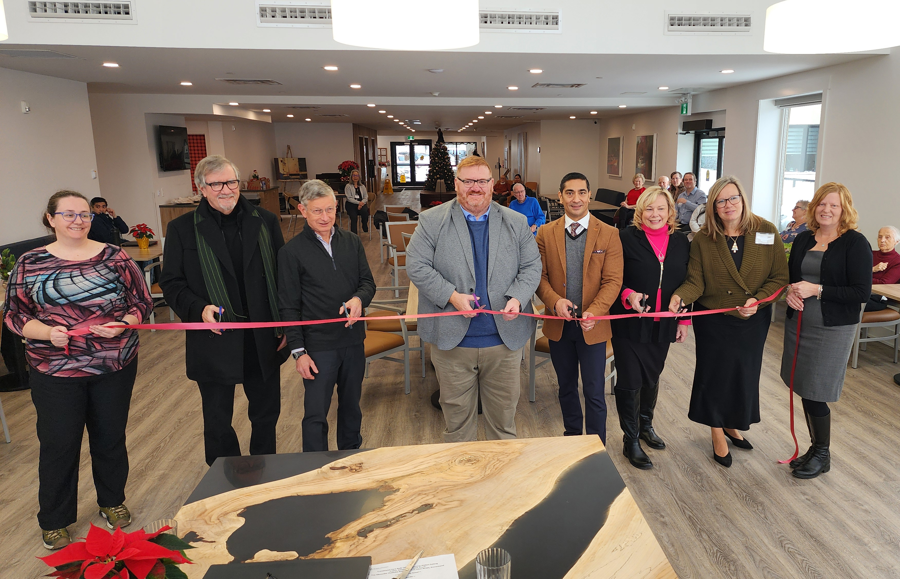 A group of people in a line cutting a red ribbon
