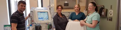 Dialysis team members with hemodialysis machine and patient chair