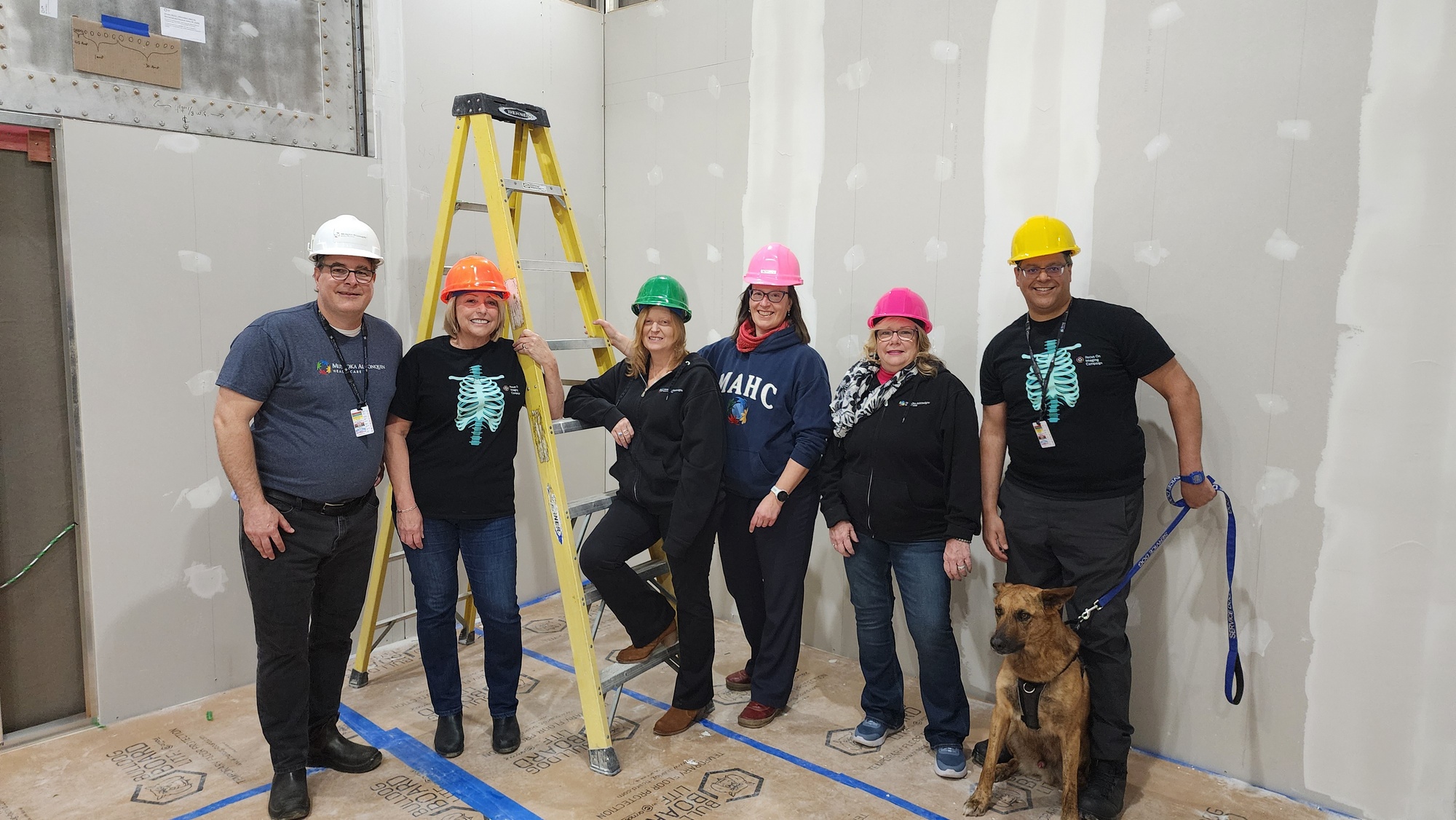 A group of staff wearing hard hats in the under-construction MRI suite