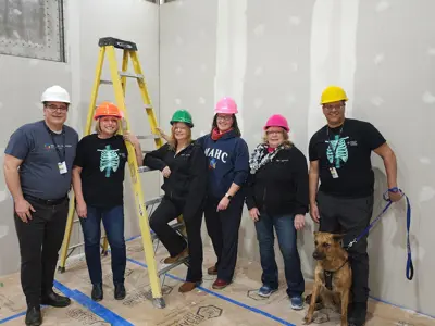 A group of staff wearing hard hats in the under-construction MRI suite